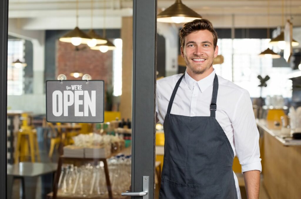 Small business owner smiling next to his store