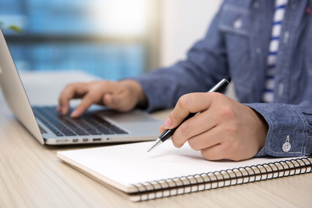 man working on computer writing notes