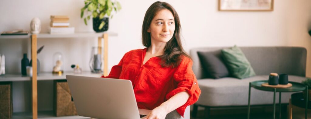 woman in a red blouse sitting with her laptop