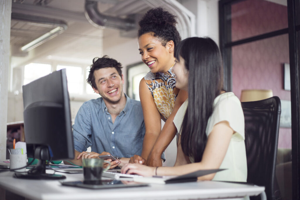 Coworkers smiling in front of computer monitor