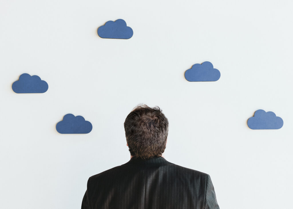 Man in suit looking at a wall decorated with clouds