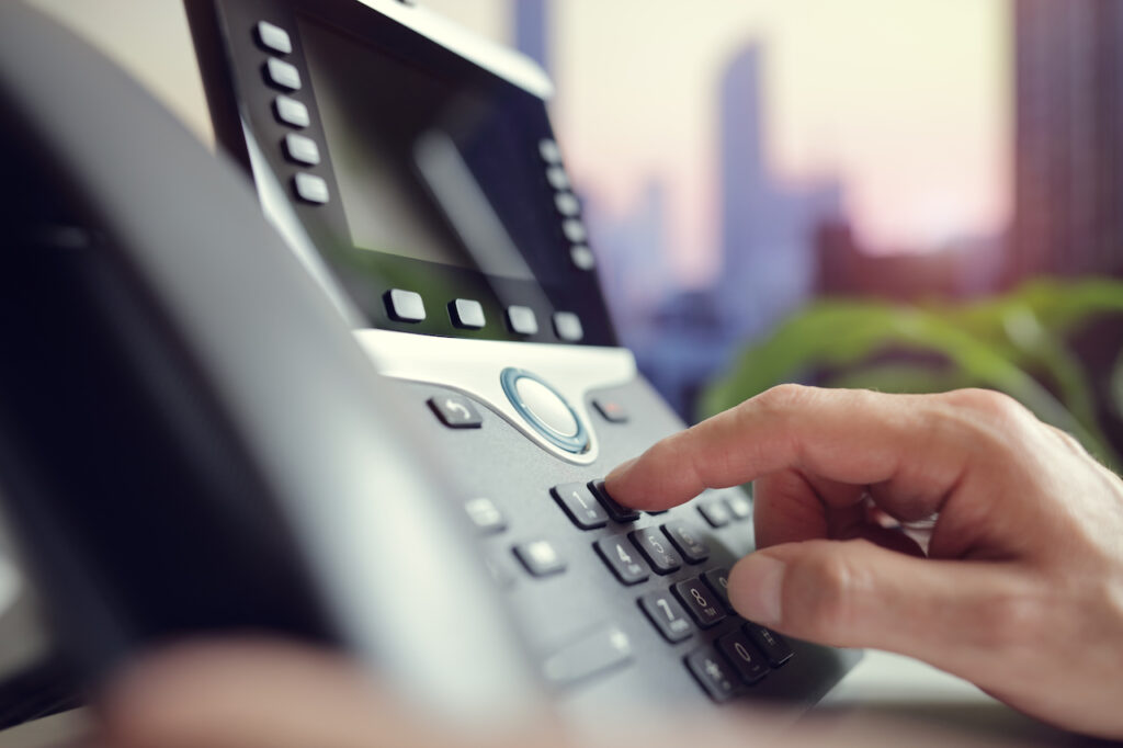 Employee using VoIP keypad to communicate with customers.